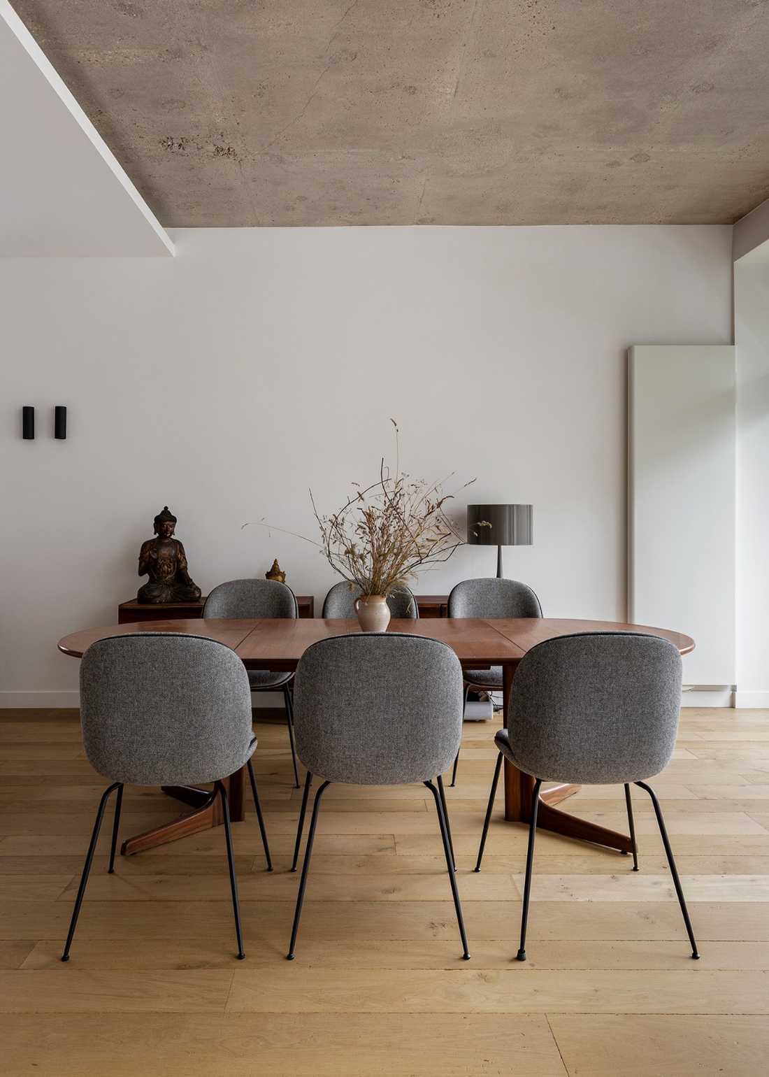 Salle à manger rénovée avec une table en noyer et des sièges en tissu gris